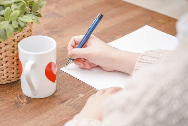 ペンを持つ女性とマグカップ